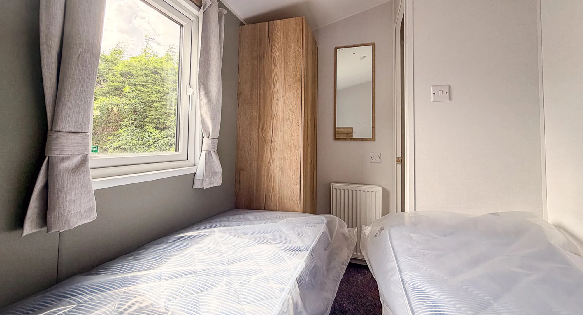 bedroom with twin beds, wooden wardrobe , mirror and radiator