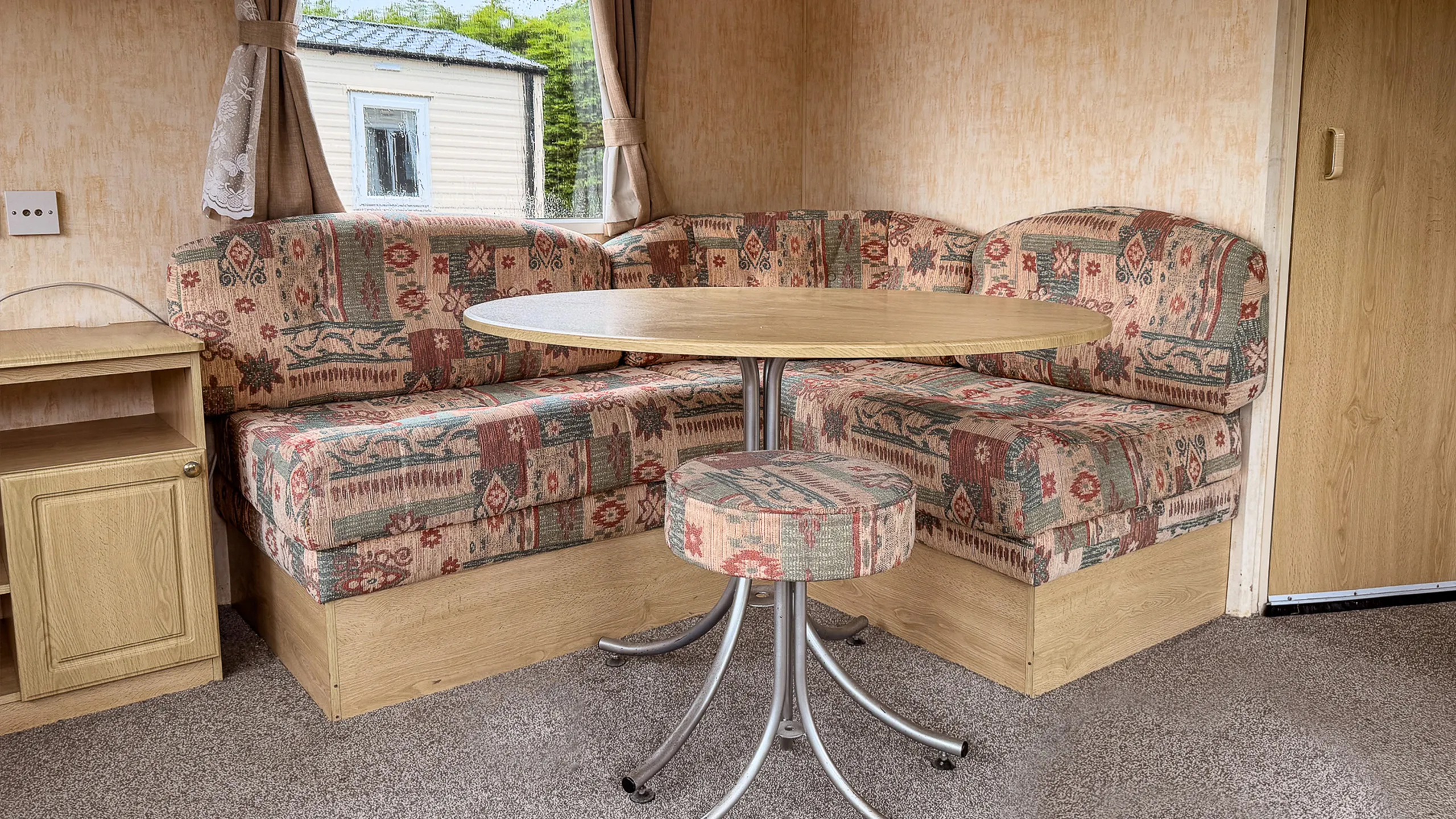 dining room with built in curved sofa, round wooden table and a stool