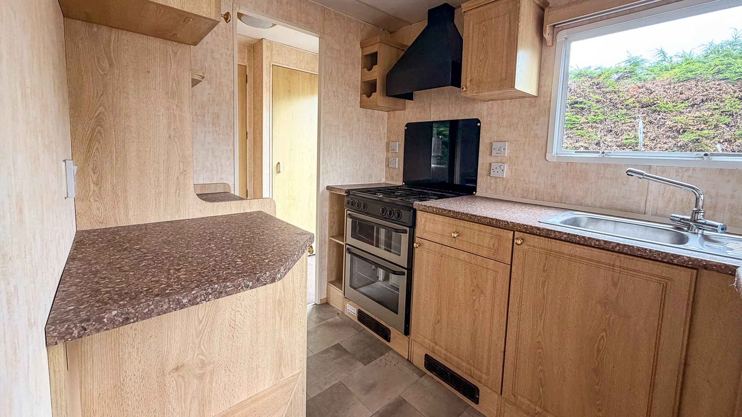 Contessa caravan interior view of a kitchen with oak coloured cabinets and black cooker