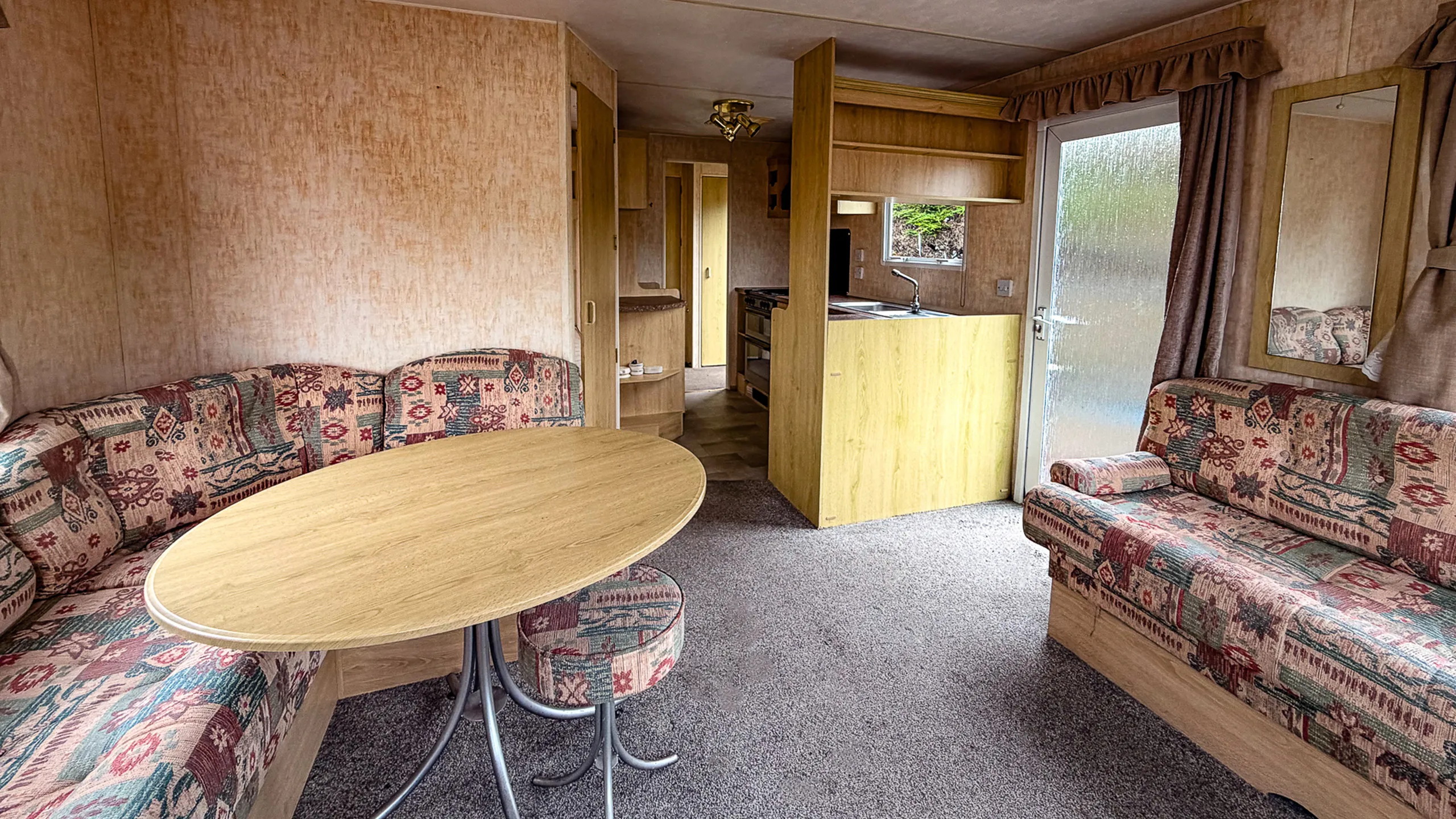 Living area with L-shaped sofa, dining table and view of the kitchen in the rear