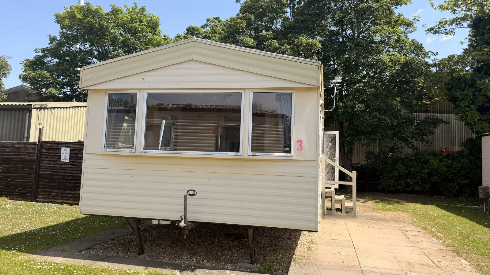 Outside view of a static caravan with a bay front window and steps going into the side door
