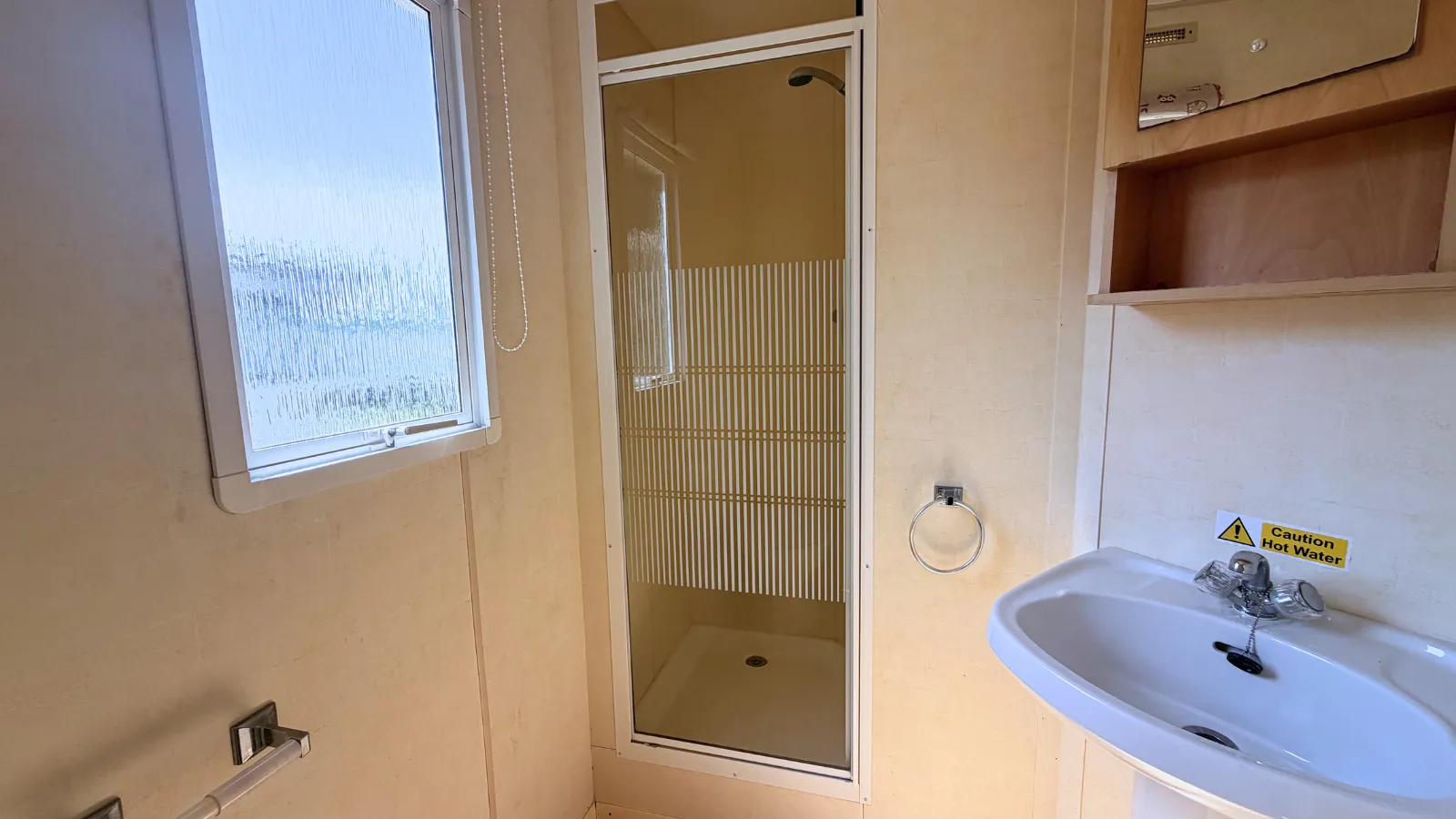 interior view of static caravan bathroom with a built-in shower stall with a glass door, and a sink