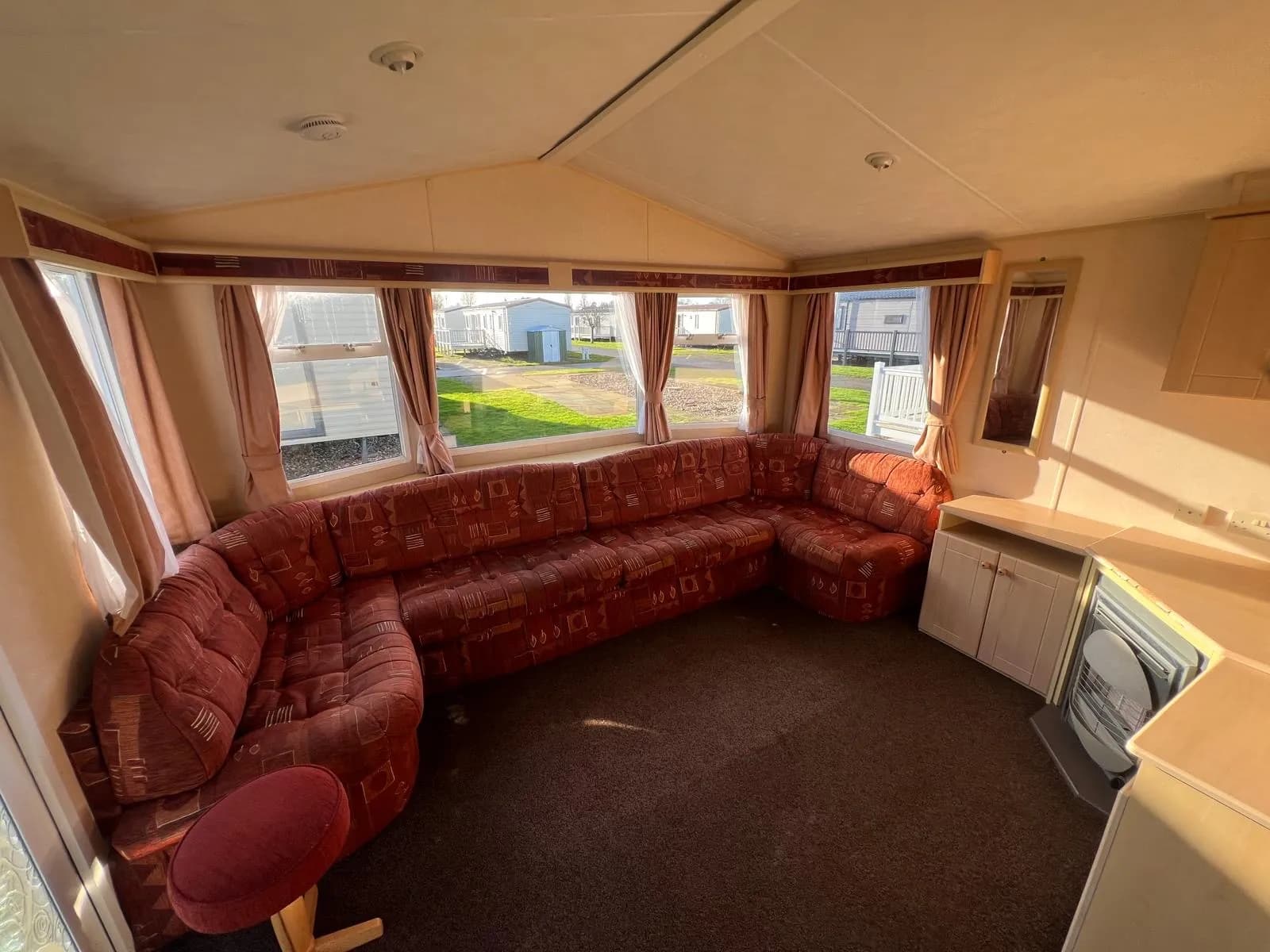 static caravan living room with built in sofa with a large bay window behind and fireplace with storage