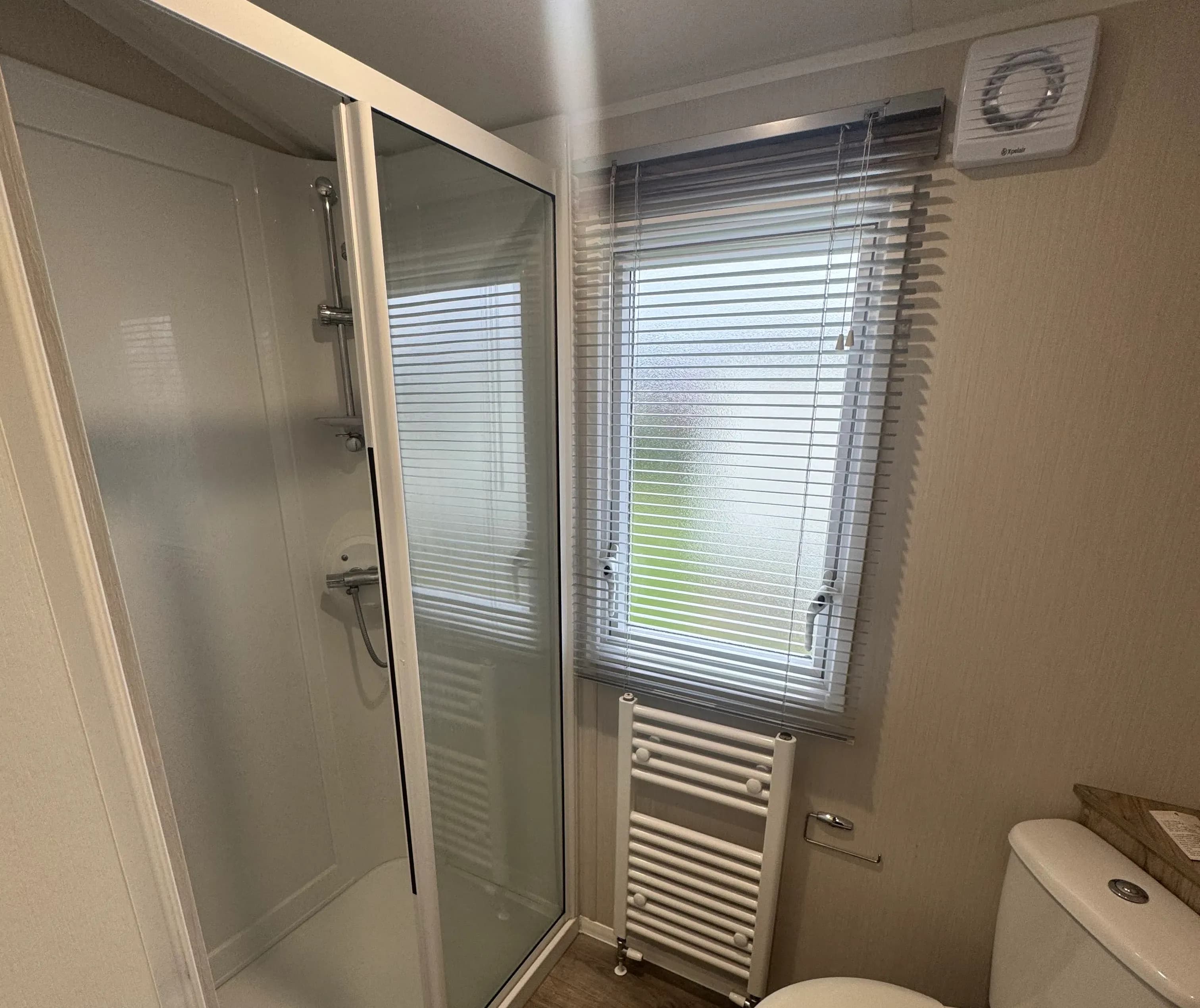 Willerby Linwood bathroom with shower stall, with glass sliding door, wood flooring and radiator