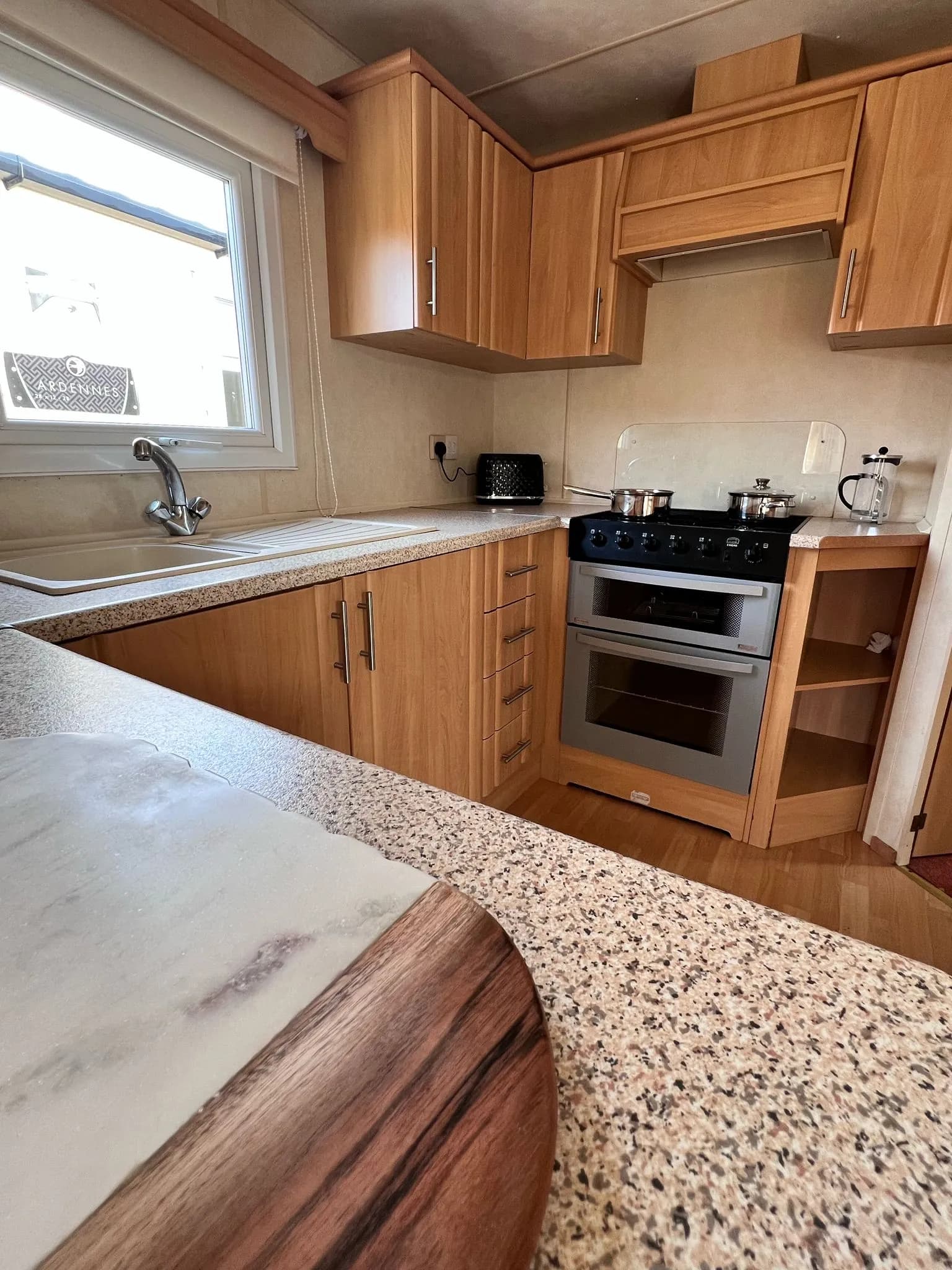 kitchen view of a stainless steel cooker built into kitchen cabinets and display shelving at the side