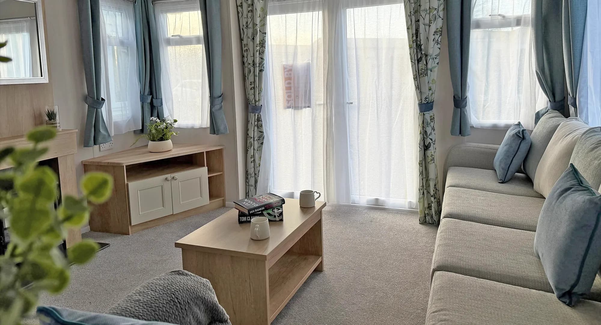 Swift Burgundy Coastfield caravan living room with large patio door, coffee table, sofa and tv stand