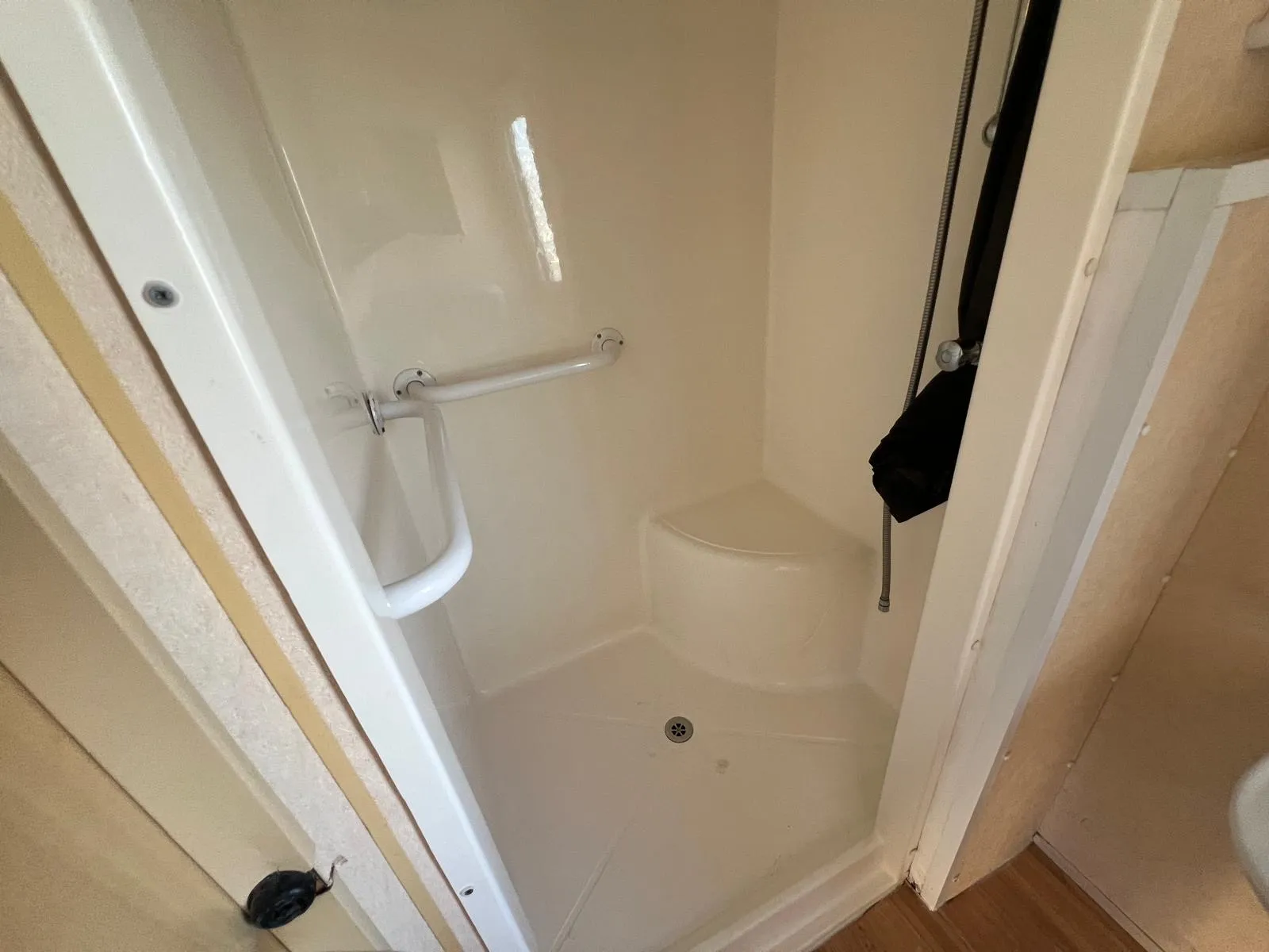 a built in shower unit in whit with a disability handle and a built in seat