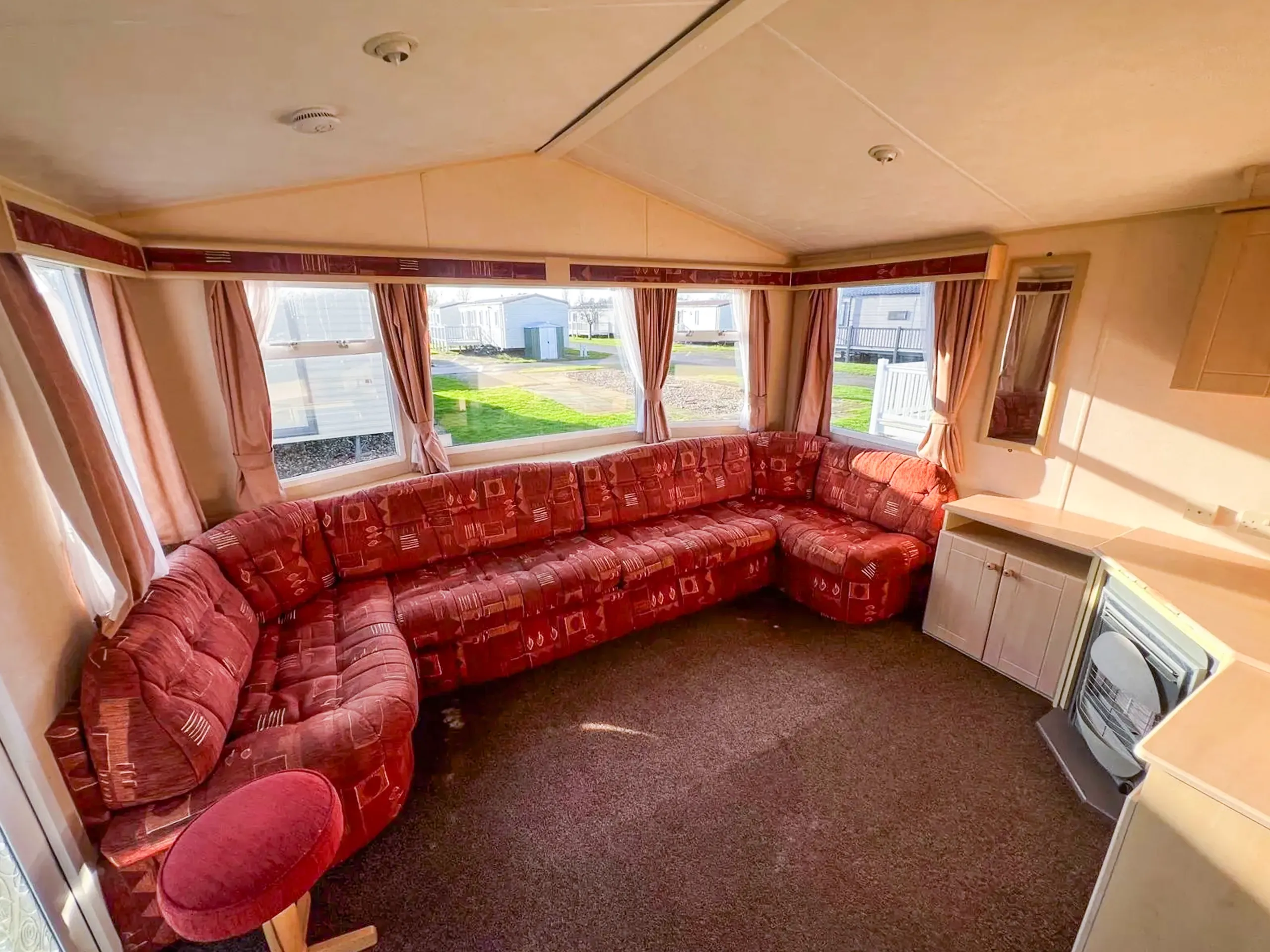 static caravan living room with built in sofa with a large bay window behind and fireplace with storage