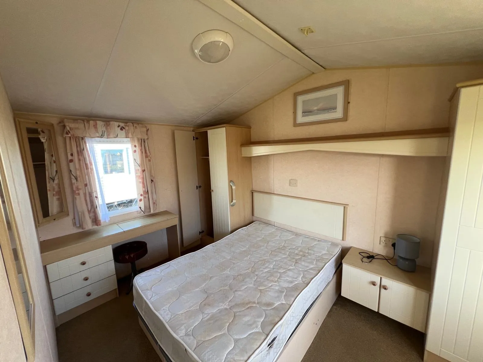 Static caravan master bedroom with double bed, dressing table, overhead storage and two wardrobes