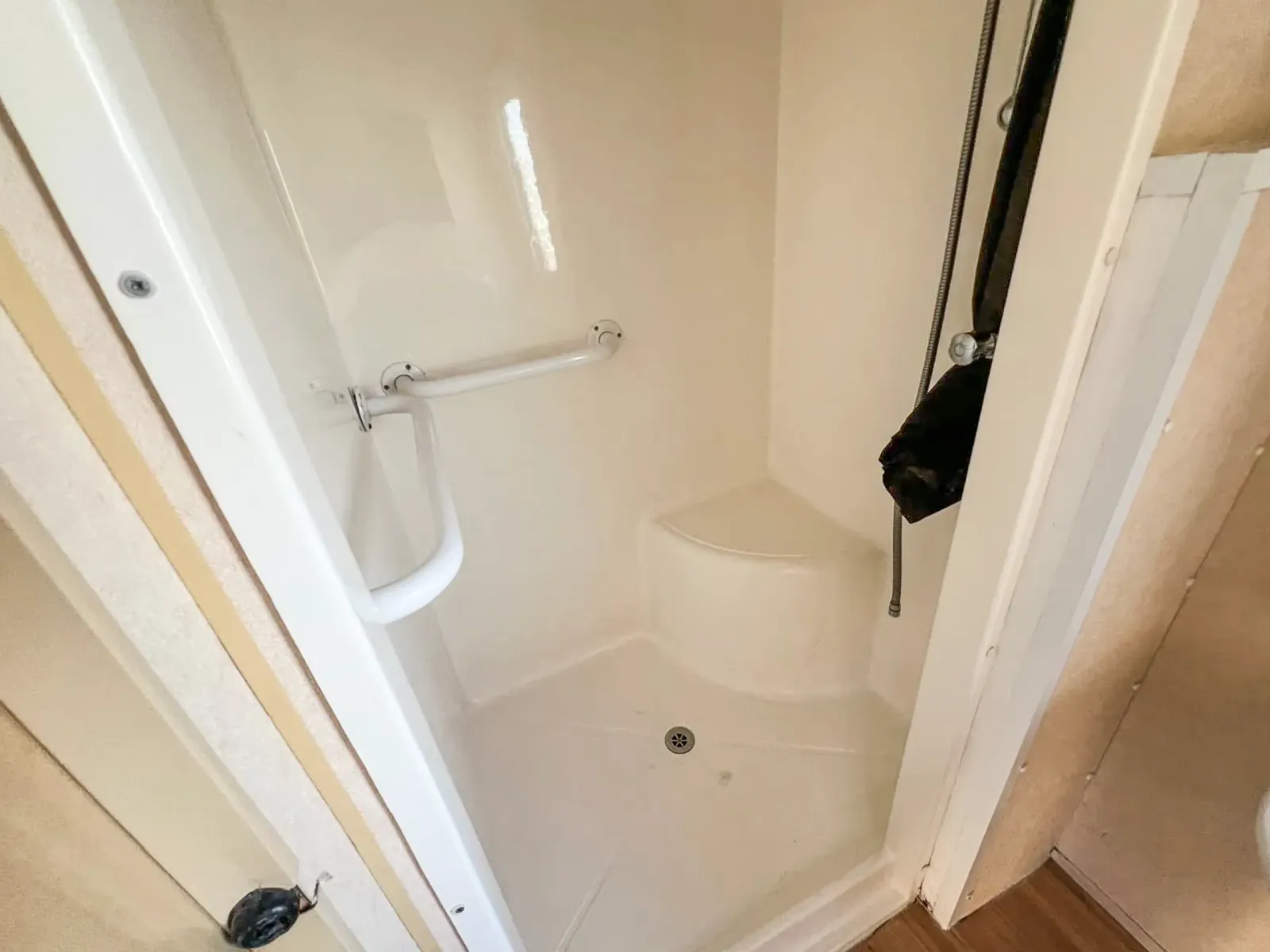 a built in shower unit in whit with a disability handle and a built in seat