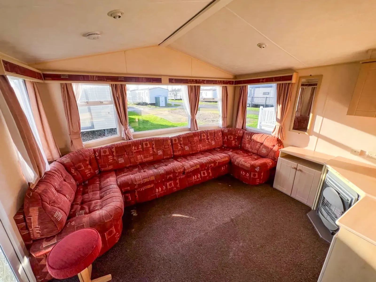 static caravan living room with built in sofa with a large bay window behind and fireplace with storage