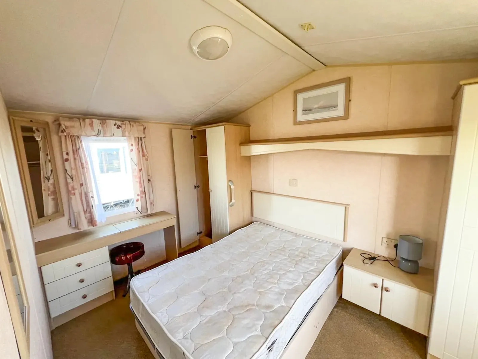 Static caravan master bedroom with double bed, dressing table, overhead storage and two wardrobes