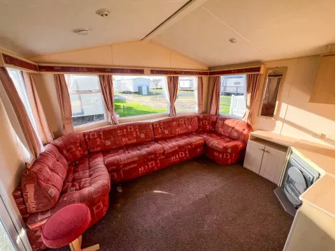 static caravan living room with built in sofa with a large bay window behind and fireplace with storage