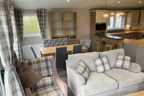 Spacious open-plan living area with kitchen island, lounge and dining space in the Willerby Portland Lodge