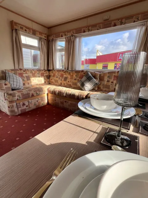 Living room on a 2008 ABI Colorado with l-shaped sofa, large rear windows and dining table
