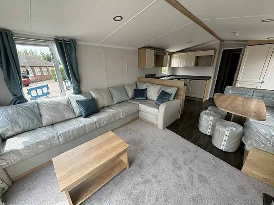 Open-plan living room in the 2023 Swift Burgundy with wraparound seating and large windows